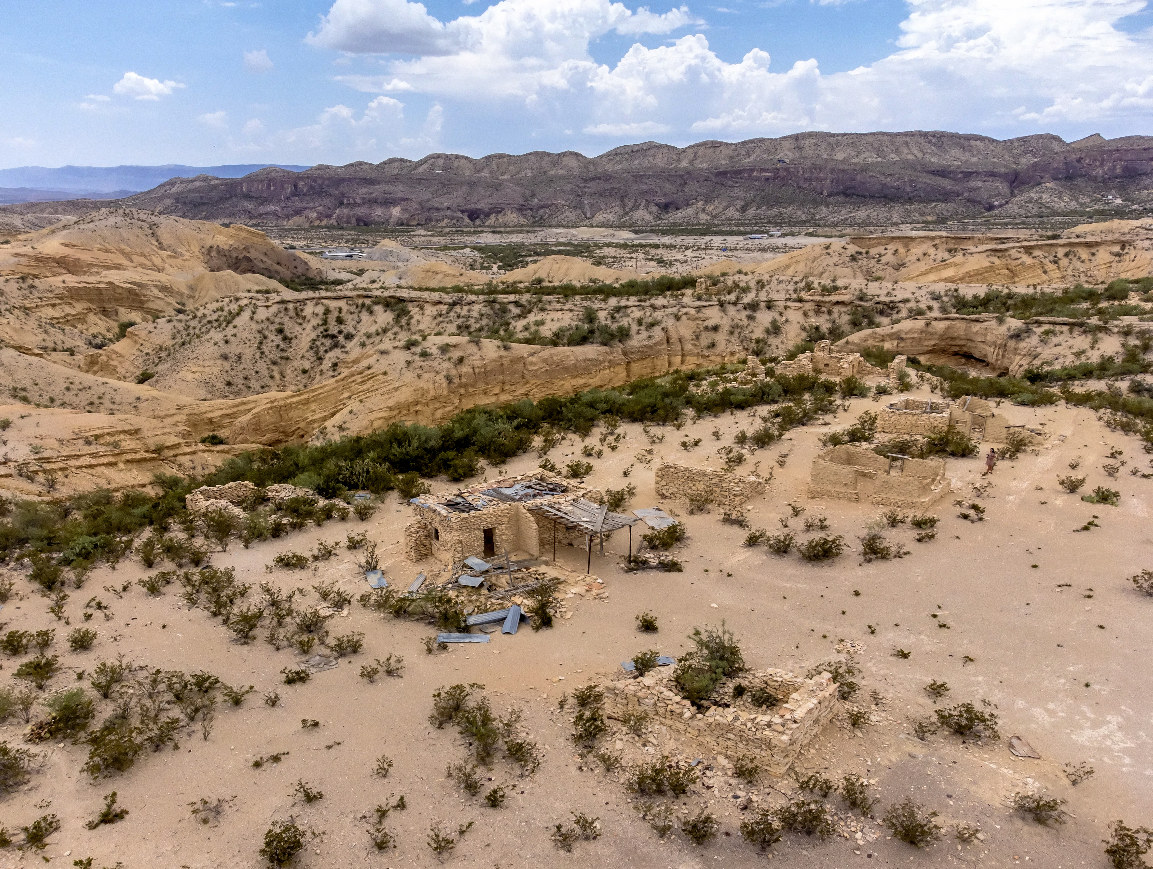Weathered stone ruins of miners homes at Terlingua, Texas, in the Chihuahuan Desert with mountains in the distance